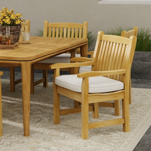 12218 Veranda Teak Dining Chair front angled view shown with an optional seat cushion next to dining table on outdoor terrace with landscape plants against a wall in the background