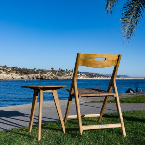 11916 Surf folding side chair and side table showing back view with ocean and blue sky background