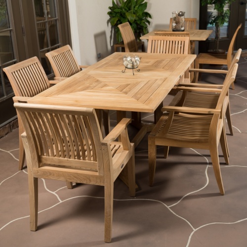 12810 Laguna Dining Armchair showing 6 around Teak Rectangular Table and 4 around a square table on an outdoor patio with potted plants and french doors in the background 