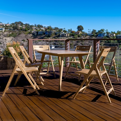 11916 Surf folding side chair showing 6 around a teak rectangular table on wood deck overlooking landscape trees and blue skies in background 